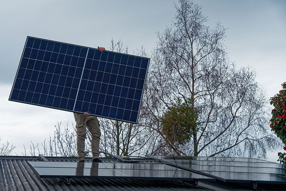 Worker installing solar panels on roof